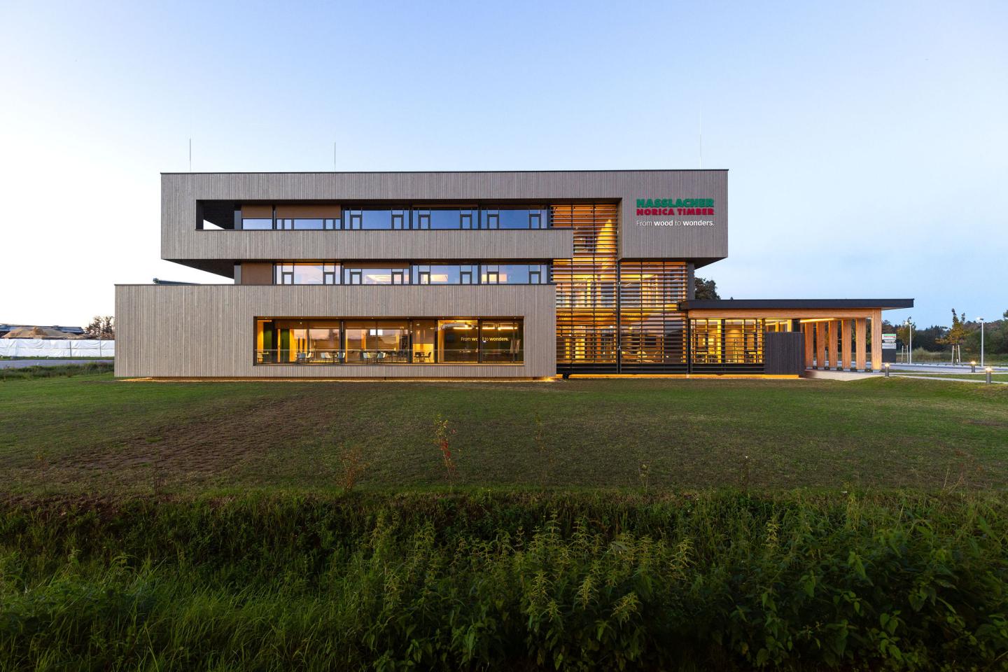 Das neue Bürogebäude der HASSLACHER PREDING Holzindustrie, Außenansicht bei Tagelicht mit Beleuchtung