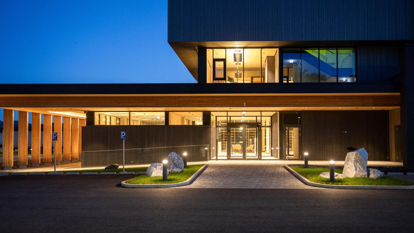 The new office building of HASSLACHER PREDING Holzindustrie, entrance area at dusk with lighting