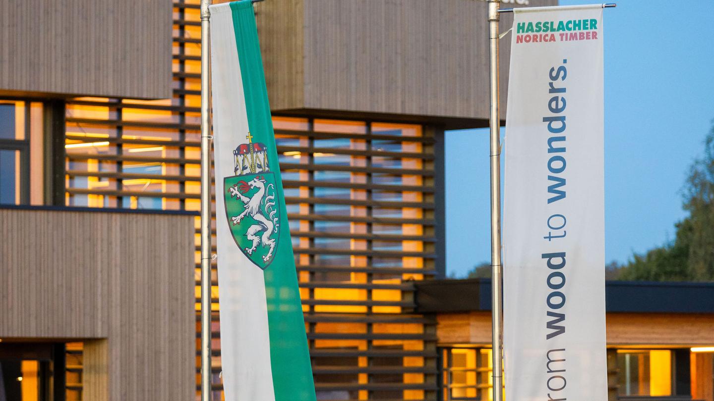 The new office building of HASSLACHER PREDING Holzindustrie, facade with flags at the car park