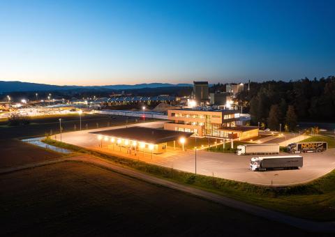 The new office building of HASSLACHER PREDING Holzindustrie, aerial view with terminal and office building at dusk and illumination