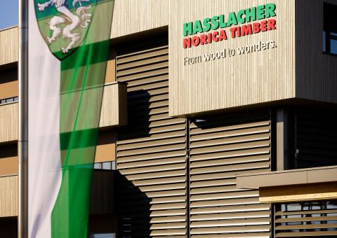 The new office building of HASSLACHER PREDING Holzindustrie, façade with logo and Styrian flag in the foreground