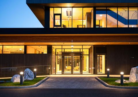 The new office building of HASSLACHER PREDING Holzindustrie, entrance area illuminated at dusk